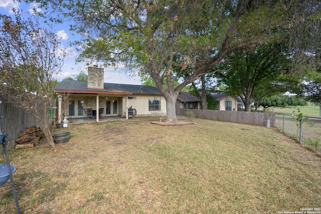 rear view of house with a lawn, french doors, a chimney, and a fenced backyard