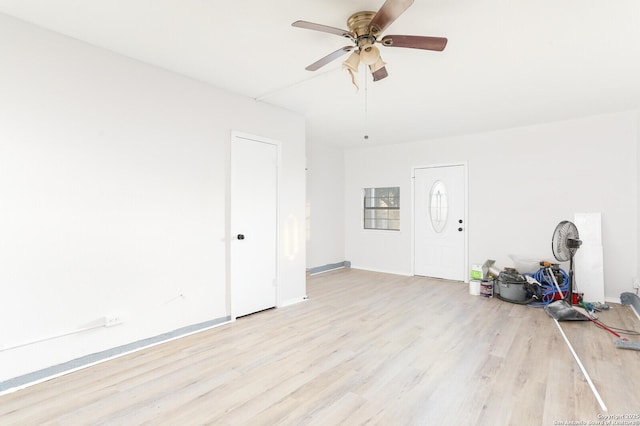 unfurnished living room featuring baseboards, a ceiling fan, and light wood-style floors