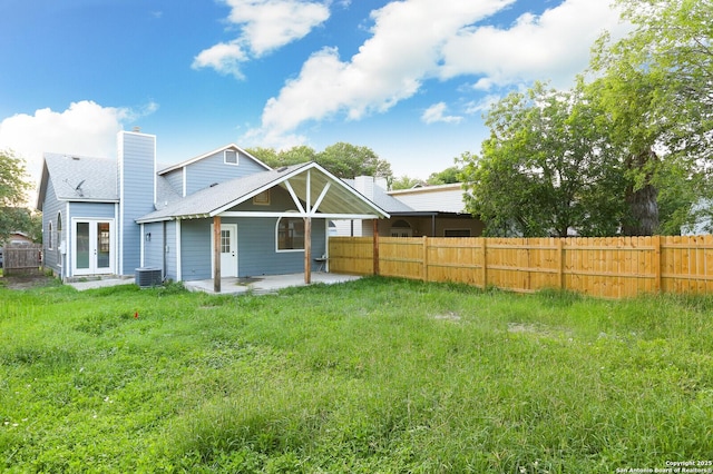 rear view of property featuring a lawn, a patio, fence, french doors, and a chimney