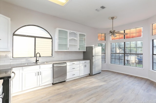 kitchen with light stone counters, visible vents, a sink, decorative backsplash, and appliances with stainless steel finishes