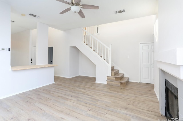 unfurnished living room with visible vents, stairway, a fireplace, and wood finished floors