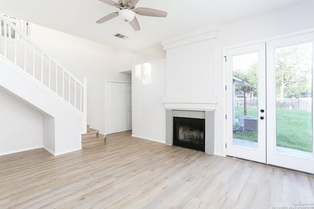 unfurnished living room with stairway, visible vents, light wood finished floors, and a tile fireplace