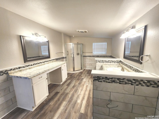 bathroom with visible vents, a wainscoted wall, a stall shower, wood finished floors, and tile walls