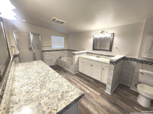 bathroom featuring wainscoting, tile walls, wood finished floors, and a shower stall