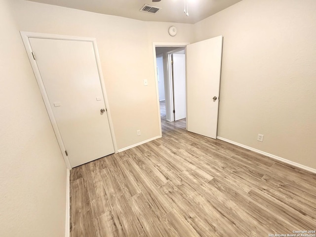 unfurnished bedroom with visible vents, baseboards, and wood finished floors