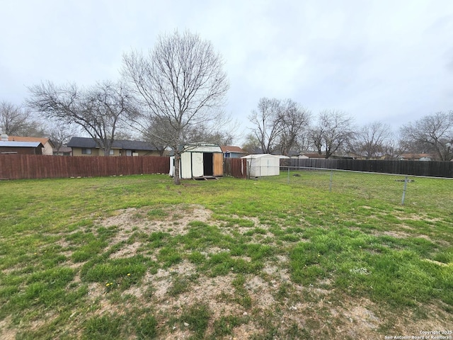 view of yard featuring an outbuilding, a storage unit, and a fenced backyard