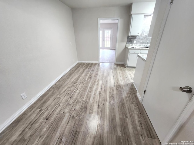 unfurnished dining area with a sink, light wood-type flooring, and baseboards