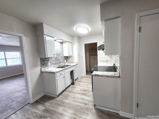 kitchen with a sink, light wood finished floors, backsplash, and light countertops