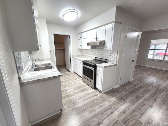 kitchen with electric stove, a sink, under cabinet range hood, light wood-style floors, and light countertops