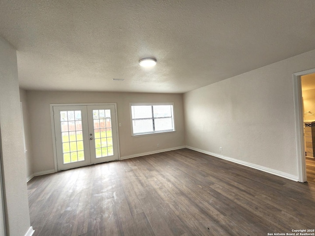 unfurnished room with visible vents, a textured ceiling, dark wood-style floors, french doors, and baseboards