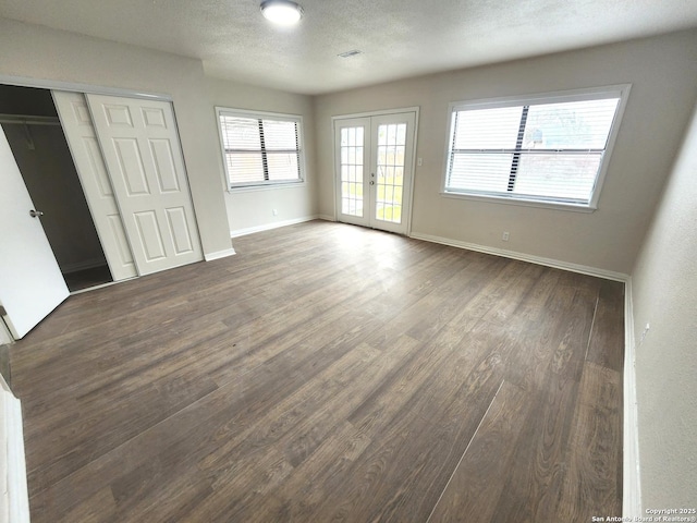 unfurnished bedroom with french doors, a textured ceiling, wood finished floors, and access to outside