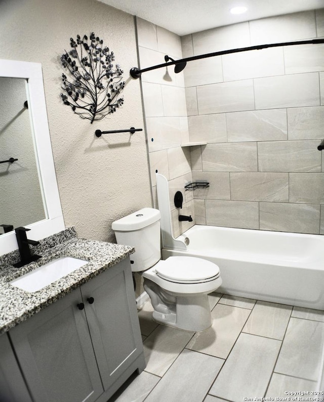 full bathroom with vanity, toilet, a textured wall, and tub / shower combination