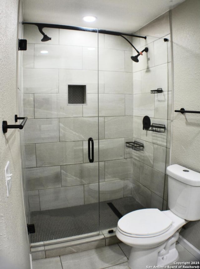 full bath featuring toilet, a stall shower, and a textured wall