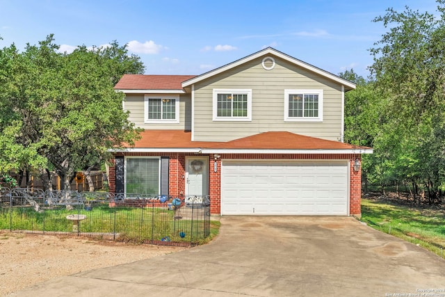 traditional-style house with brick siding, an attached garage, concrete driveway, and a fenced front yard