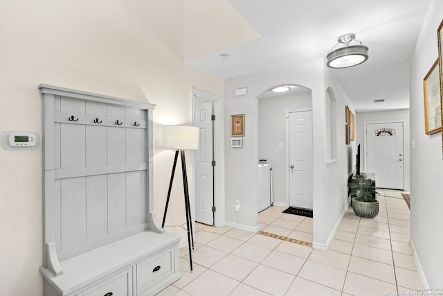 mudroom with baseboards, arched walkways, independent washer and dryer, and light tile patterned flooring