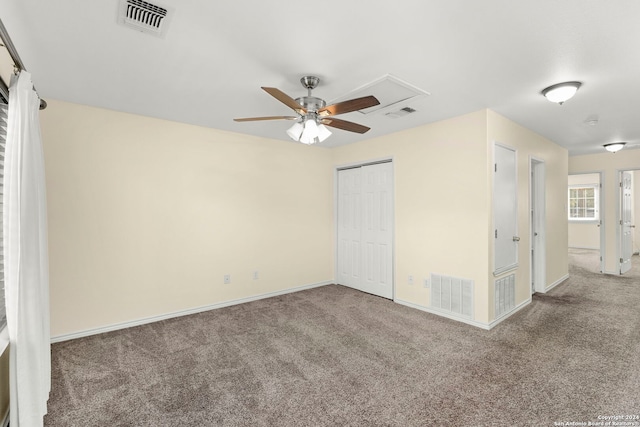 carpeted spare room with visible vents, baseboards, and a ceiling fan