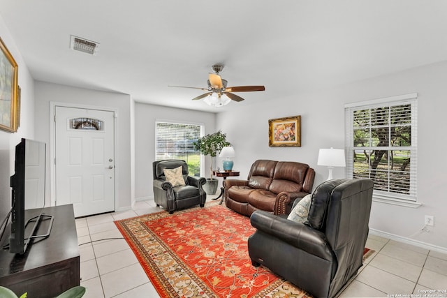 living area featuring light tile patterned floors, a ceiling fan, visible vents, and baseboards