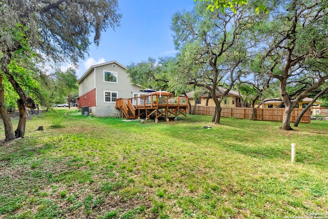 view of yard with a wooden deck, stairs, and fence