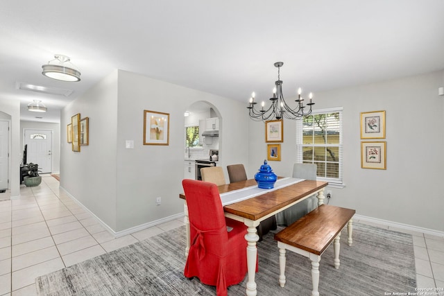 dining area featuring light tile patterned floors, baseboards, arched walkways, and a chandelier