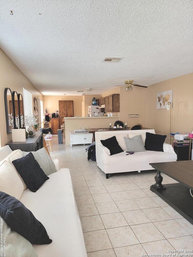 living area with light tile patterned floors, visible vents, and a textured ceiling