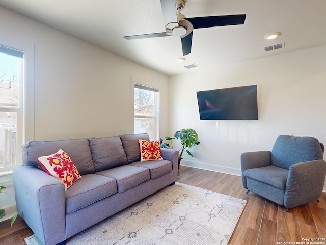 living area featuring ceiling fan, wood finished floors, visible vents, and baseboards