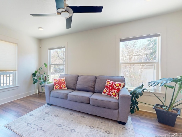 living area featuring ceiling fan, baseboards, and wood finished floors