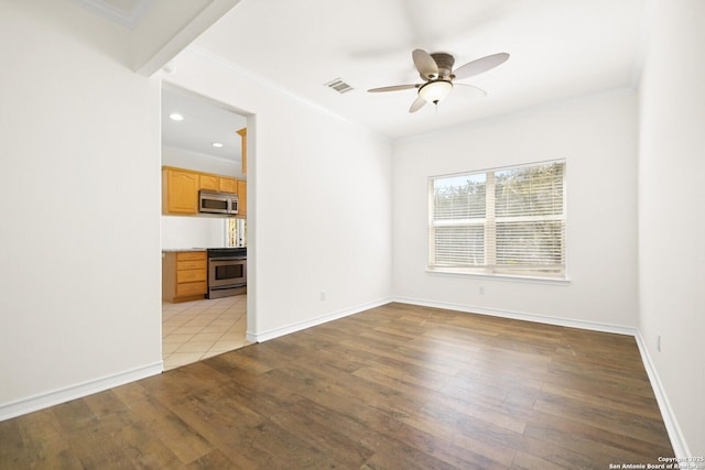 empty room with visible vents, baseboards, ceiling fan, light wood-style floors, and crown molding