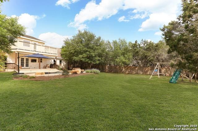 view of yard featuring french doors, a patio, fence, and a playground
