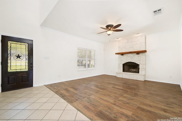 unfurnished living room featuring baseboards, visible vents, light wood-style flooring, a fireplace, and ceiling fan