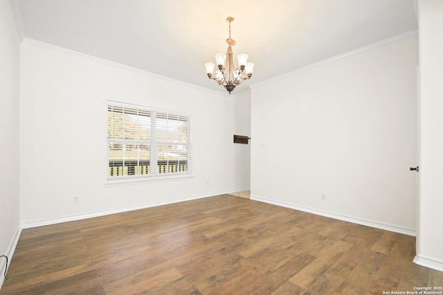 unfurnished room featuring a notable chandelier, crown molding, baseboards, and wood finished floors