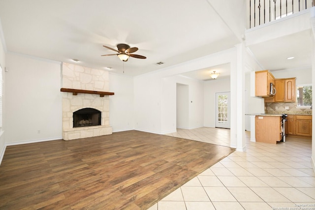 unfurnished living room with visible vents, ornamental molding, a ceiling fan, light wood-style floors, and a fireplace