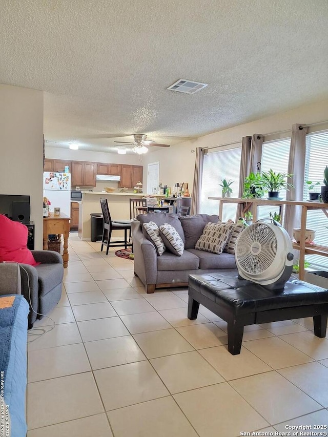 living area with light tile patterned floors, visible vents, plenty of natural light, and a textured ceiling