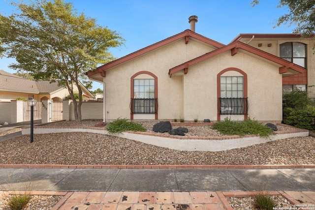 view of front of house with a gate, fence, and stucco siding