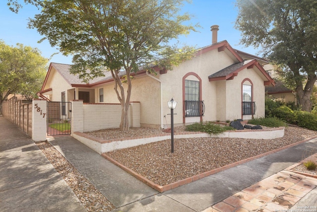 view of front of home with a fenced front yard, stucco siding, and a gate