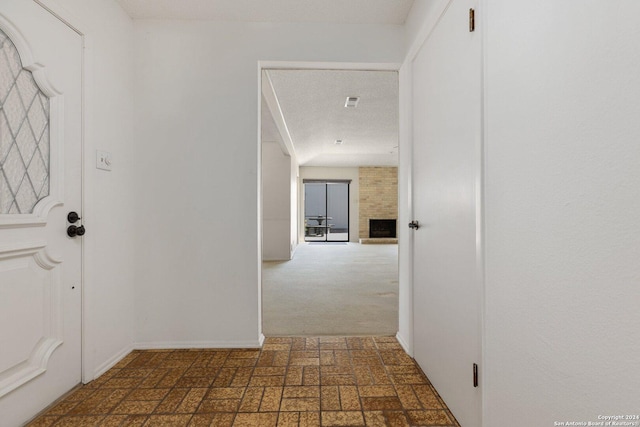 hallway featuring carpet flooring, a textured ceiling, and baseboards