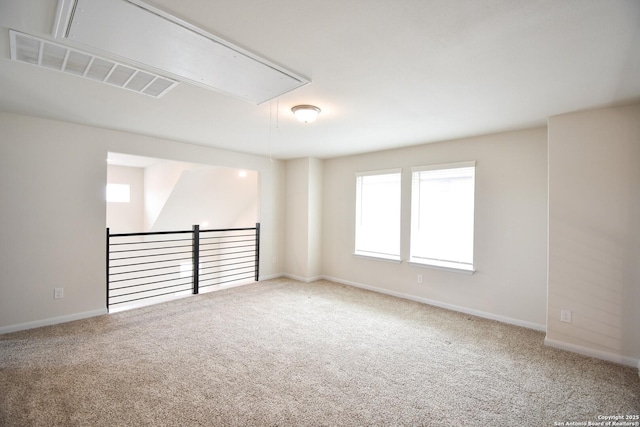 unfurnished room with attic access, carpet, and baseboards