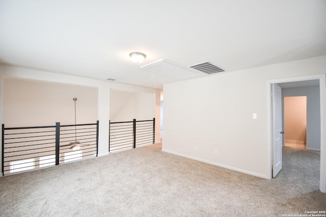 empty room with attic access, carpet flooring, baseboards, and visible vents