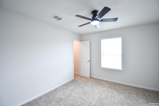 empty room featuring visible vents, carpet flooring, a ceiling fan, and baseboards