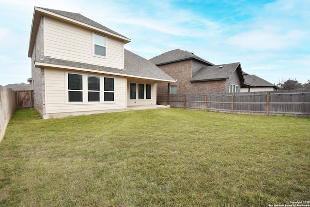 back of property with a fenced backyard, a patio, a yard, and roof with shingles