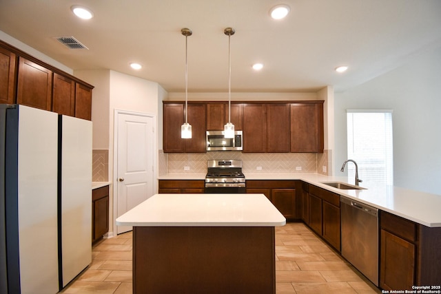 kitchen featuring visible vents, a peninsula, a sink, light countertops, and appliances with stainless steel finishes