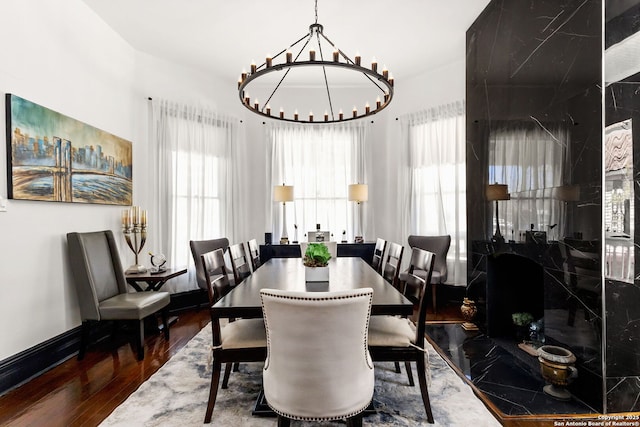 dining space with a chandelier, a healthy amount of sunlight, baseboards, and wood finished floors