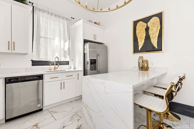 kitchen with a breakfast bar, appliances with stainless steel finishes, white cabinets, marble finish floor, and a sink