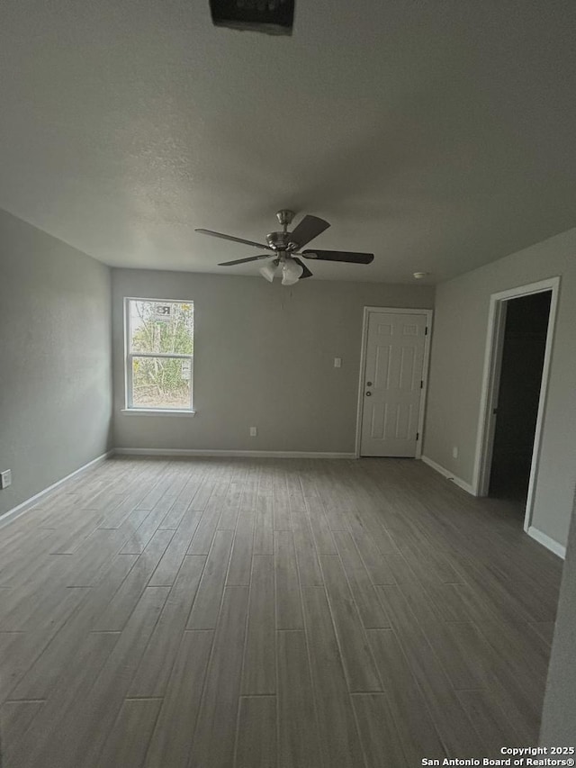 spare room with wood finished floors, baseboards, and ceiling fan