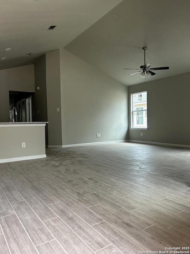 unfurnished living room with vaulted ceiling, a ceiling fan, baseboards, and visible vents