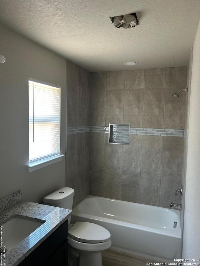 bathroom with a textured ceiling, toilet, and bathtub / shower combination