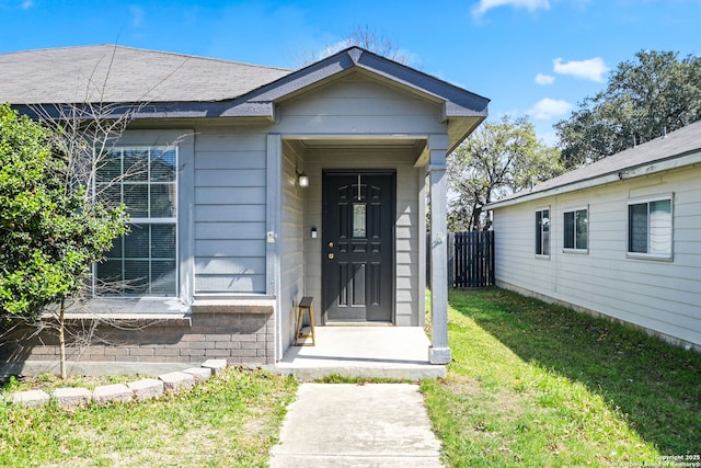 entrance to property with a lawn and fence