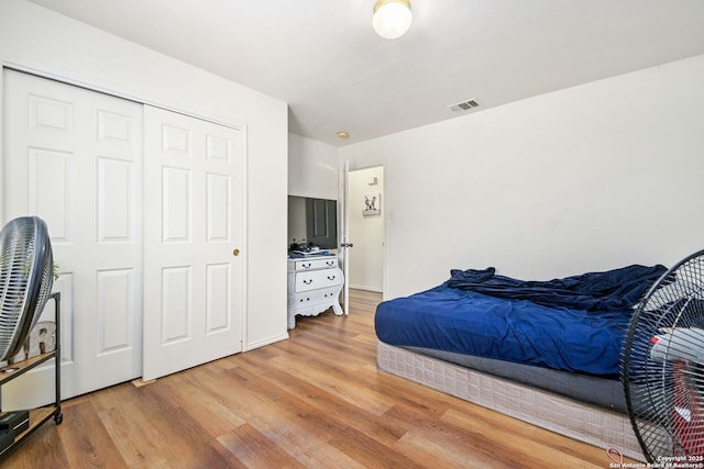 bedroom featuring light wood-style floors, visible vents, and a closet