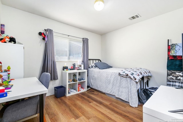 bedroom with fridge, wood finished floors, and visible vents