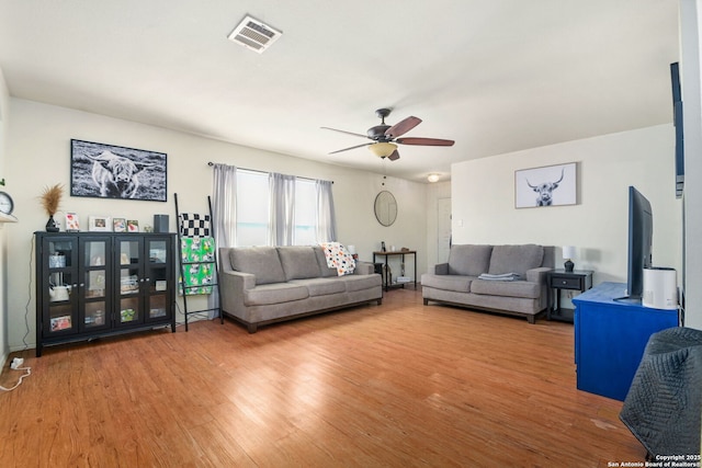 living area with visible vents, wood finished floors, and a ceiling fan