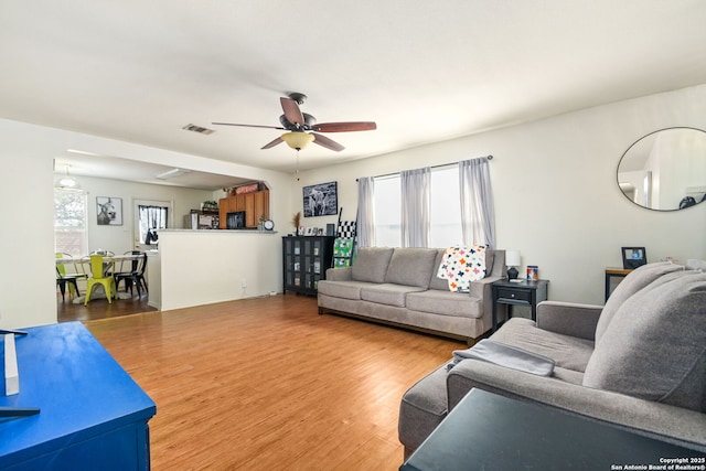 living area featuring ceiling fan, visible vents, plenty of natural light, and wood finished floors